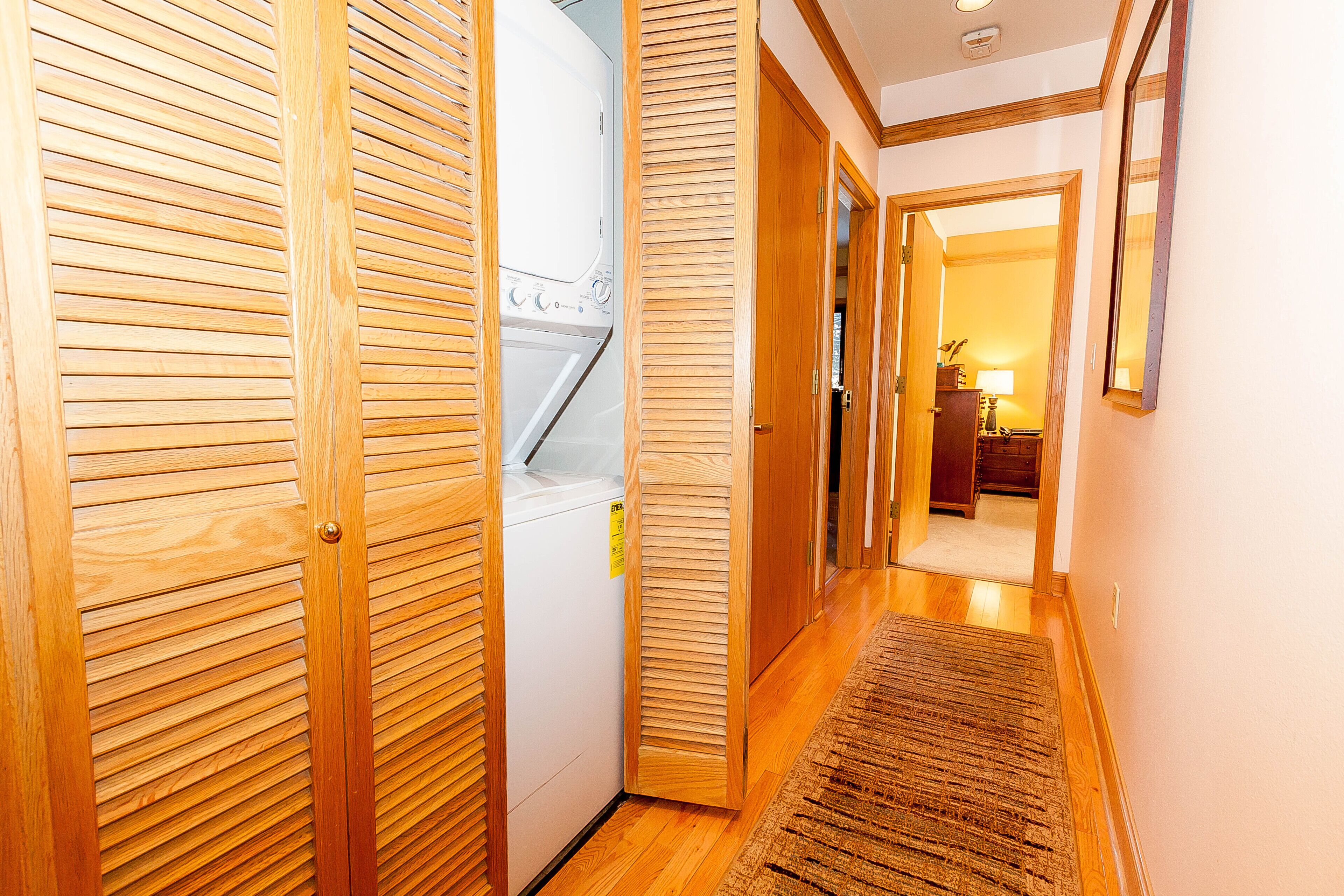 A hallway with wooden doors, a washing machine, and a rug.