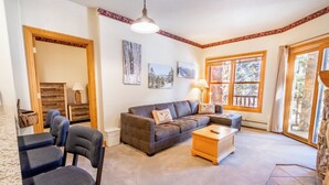 A cozy living room with a brown sofa, two armchairs, a wooden coffee table, and a fireplace.