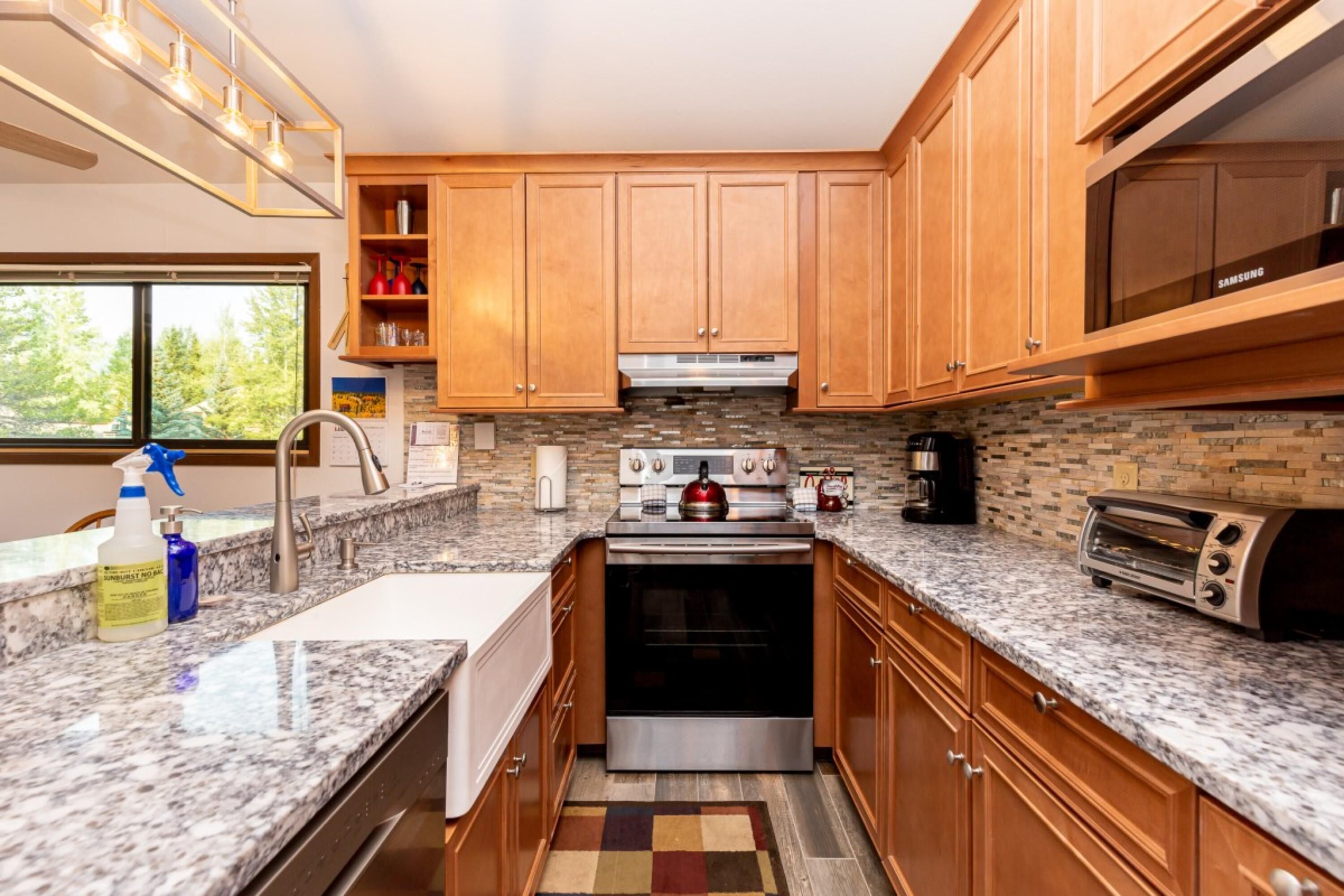 A modern kitchen with wooden cabinets, a stainless steel stove, a microwave, and a toaster.
