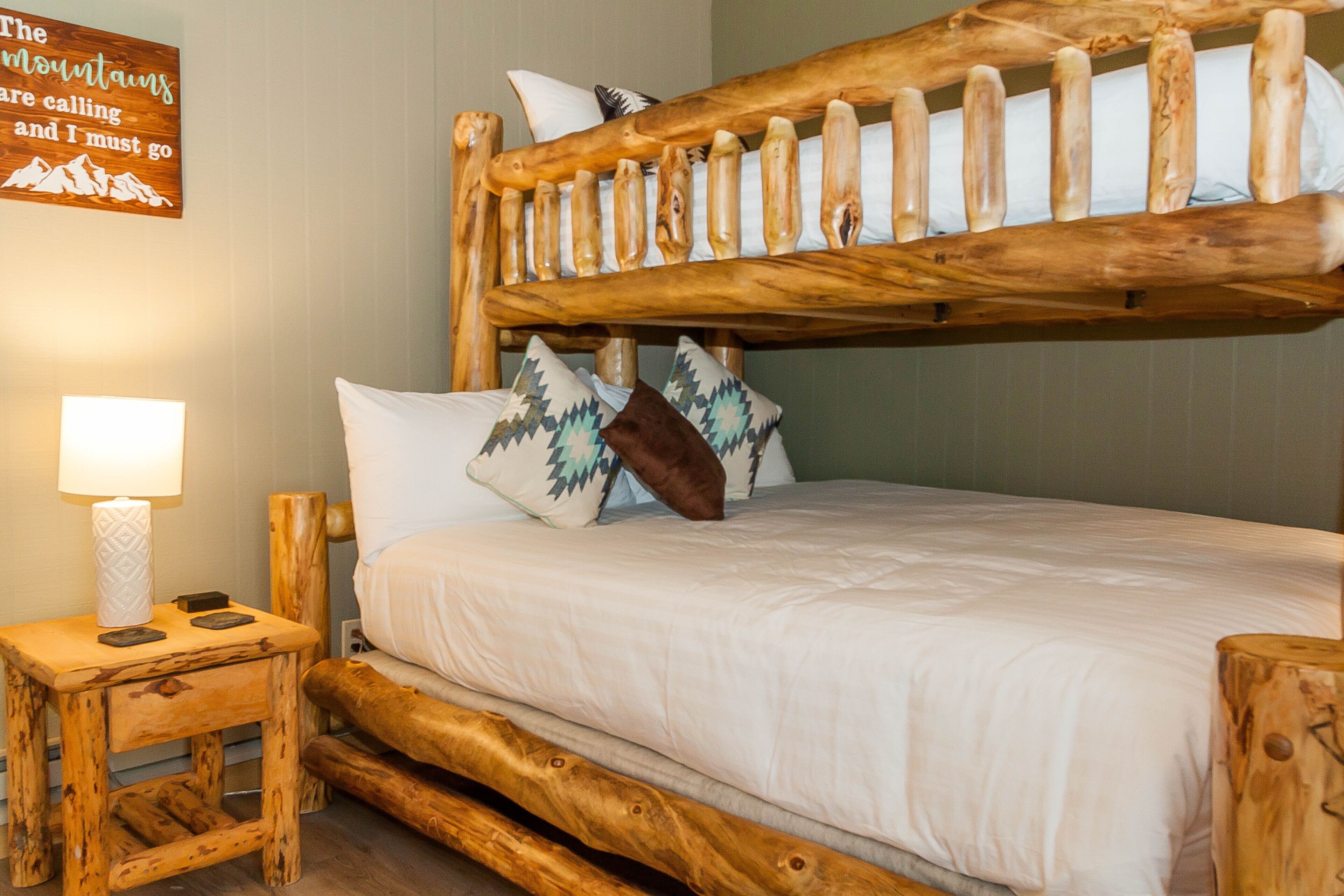 A bunk bed with a wooden frame, white bedding, and decorative pillows.