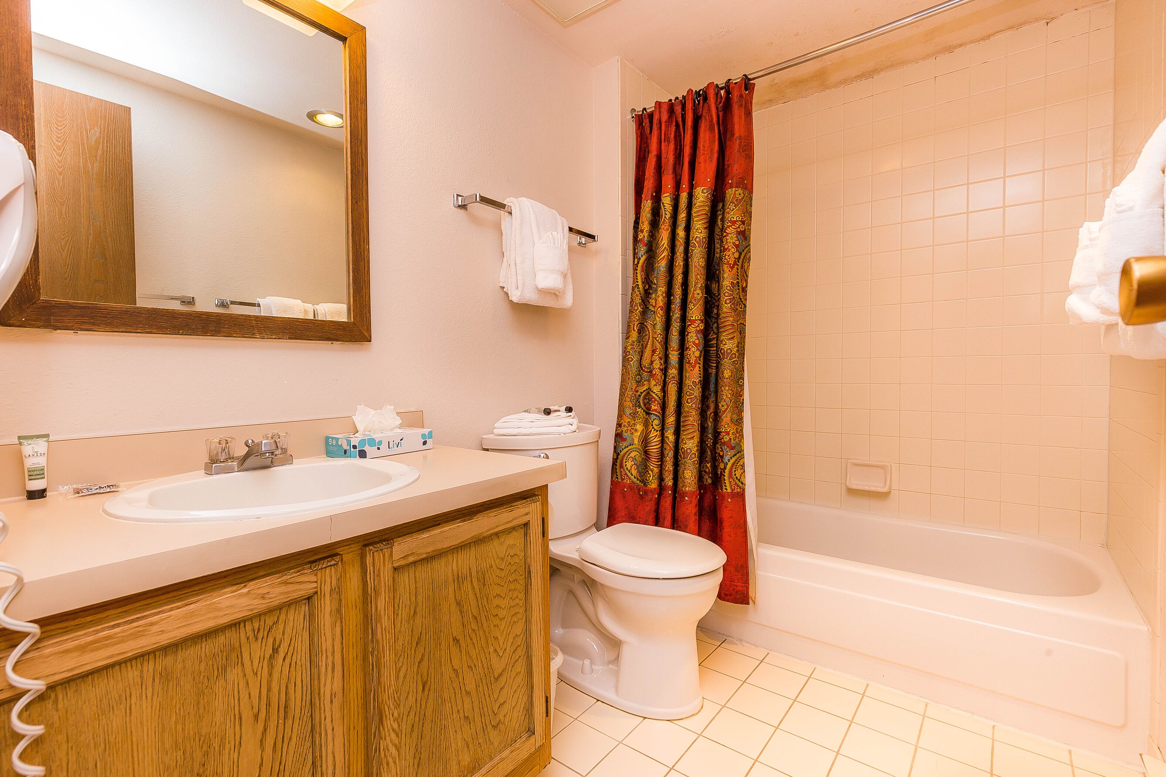 A bathroom with a wooden vanity, a white sink, a toilet, and a bathtub.