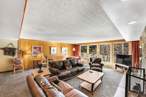 A spacious living room with a large window, leather sofas, a flat-screen TV, and a wooden ceiling. - Decatur #1787 by Summit County Mountain Retreats (Keystone)