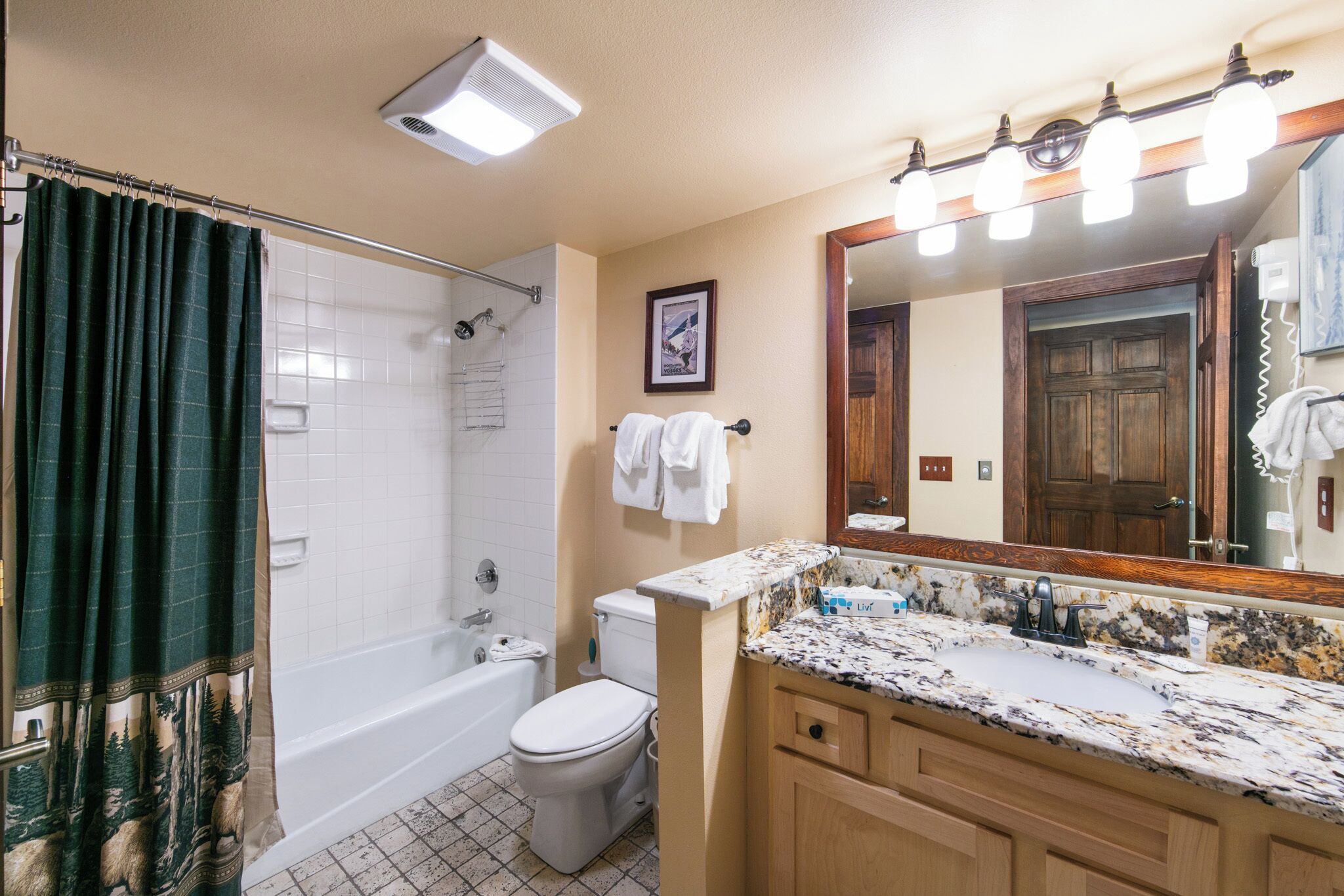 A bathroom with a shower, toilet, sink, and a large mirror.