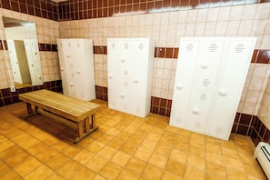 Un baño con taquillas, un banco y un espejo.