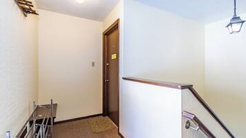 A hallway with a wooden door, a metal rack, and a carpeted floor.
