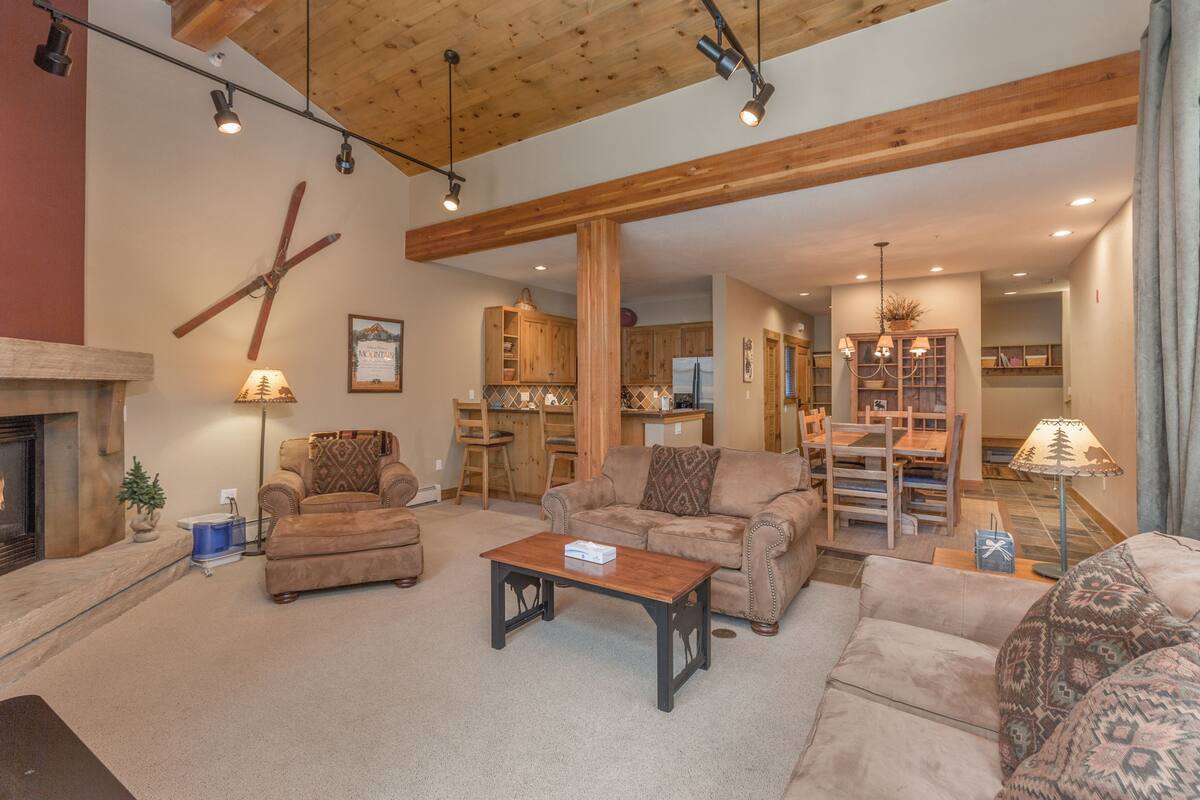 A spacious living room with a fireplace, wooden beams, and a cozy seating area.