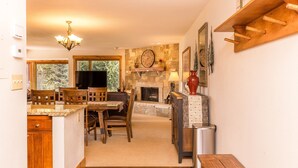 Une cuisine chaleureuse avec une cheminée en pierre, des meubles en bois et un lustre.