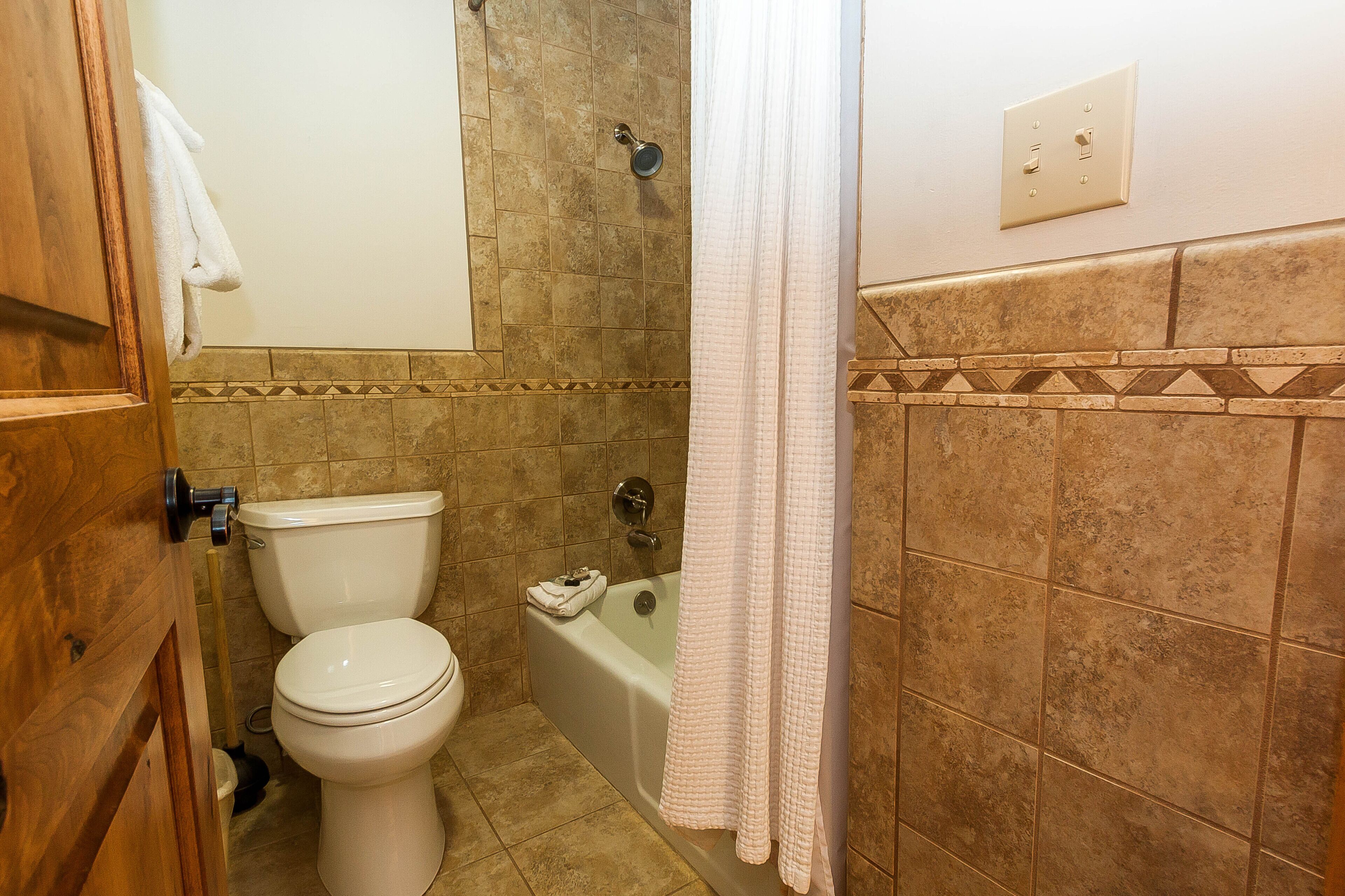 A bathroom with a toilet, bathtub, and shower curtain.