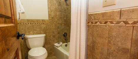 A bathroom with a toilet, bathtub, and shower curtain.