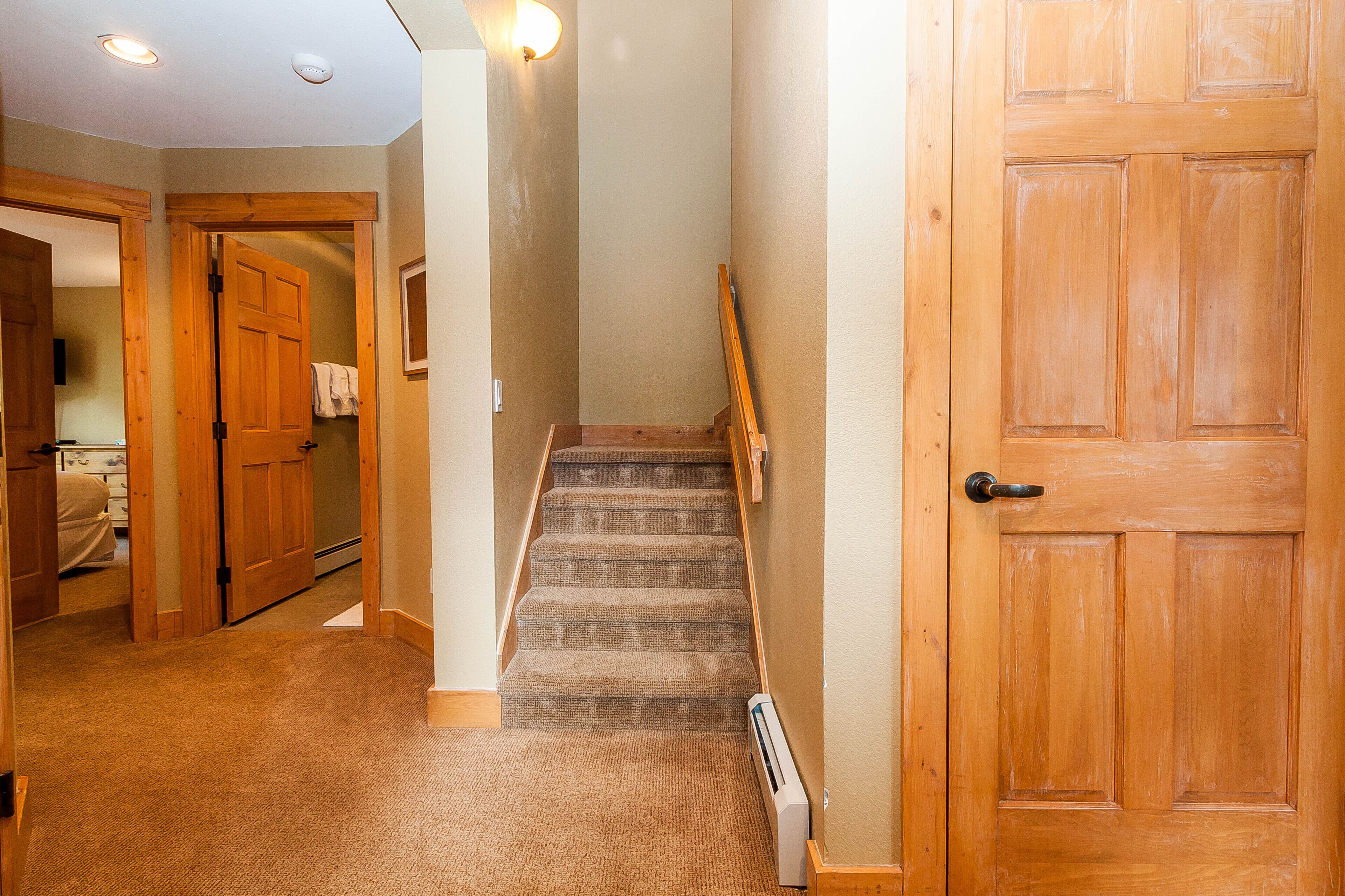 A carpeted hallway with wooden doors and a staircase.