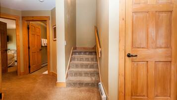 A carpeted hallway with wooden doors and a staircase.