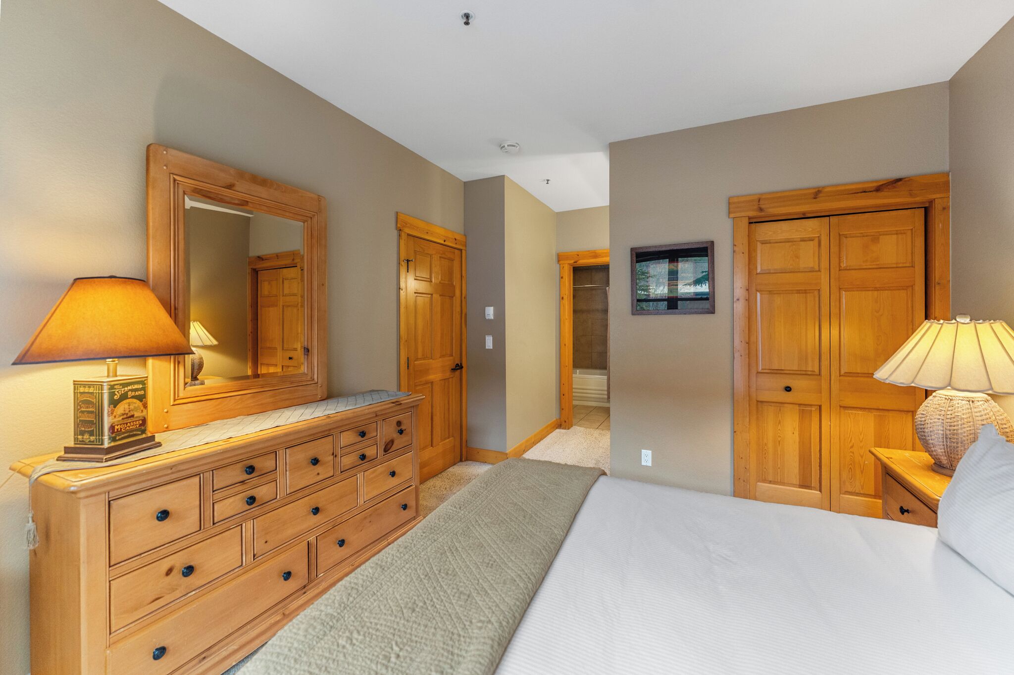 A bedroom with a wooden dresser, a bed, and two wooden wardrobes.