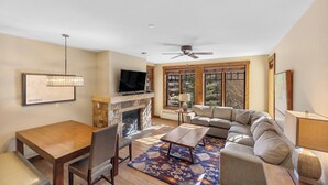 A modern living room with a fireplace, a television, a sofa, and a dining area. - Water House #6204 by Summit County Mountain Retreats (Breckenridge)