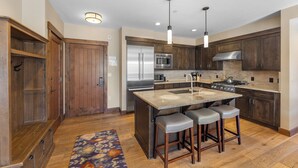 A modern kitchen with wooden cabinets, stainless steel appliances, and a central island with bar stools. - Water House #6204 by Summit County Mountain Retreats (Breckenridge)
