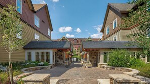 A courtyard with stone planters, a central pathway, and buildings with brown and beige siding. - Water House #6204 by Summit County Mountain Retreats (Breckenridge)