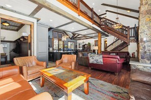 A spacious living area with leather sofas, a wooden coffee table, and a staircase leading to an upper level. - Soda Ridge 1608 by Summit County Mountain Retreats (Keystone)