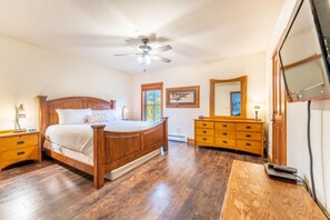 Ein Schlafzimmer mit einem hölzernen Bett, einem Schminktisch, einem Spiegel und einem Deckenventilator.