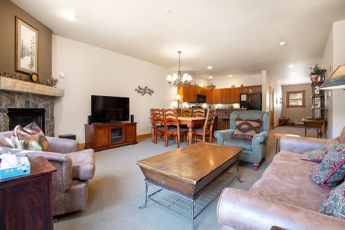 A living room with a fireplace, a television, and a dining area with wooden furniture.