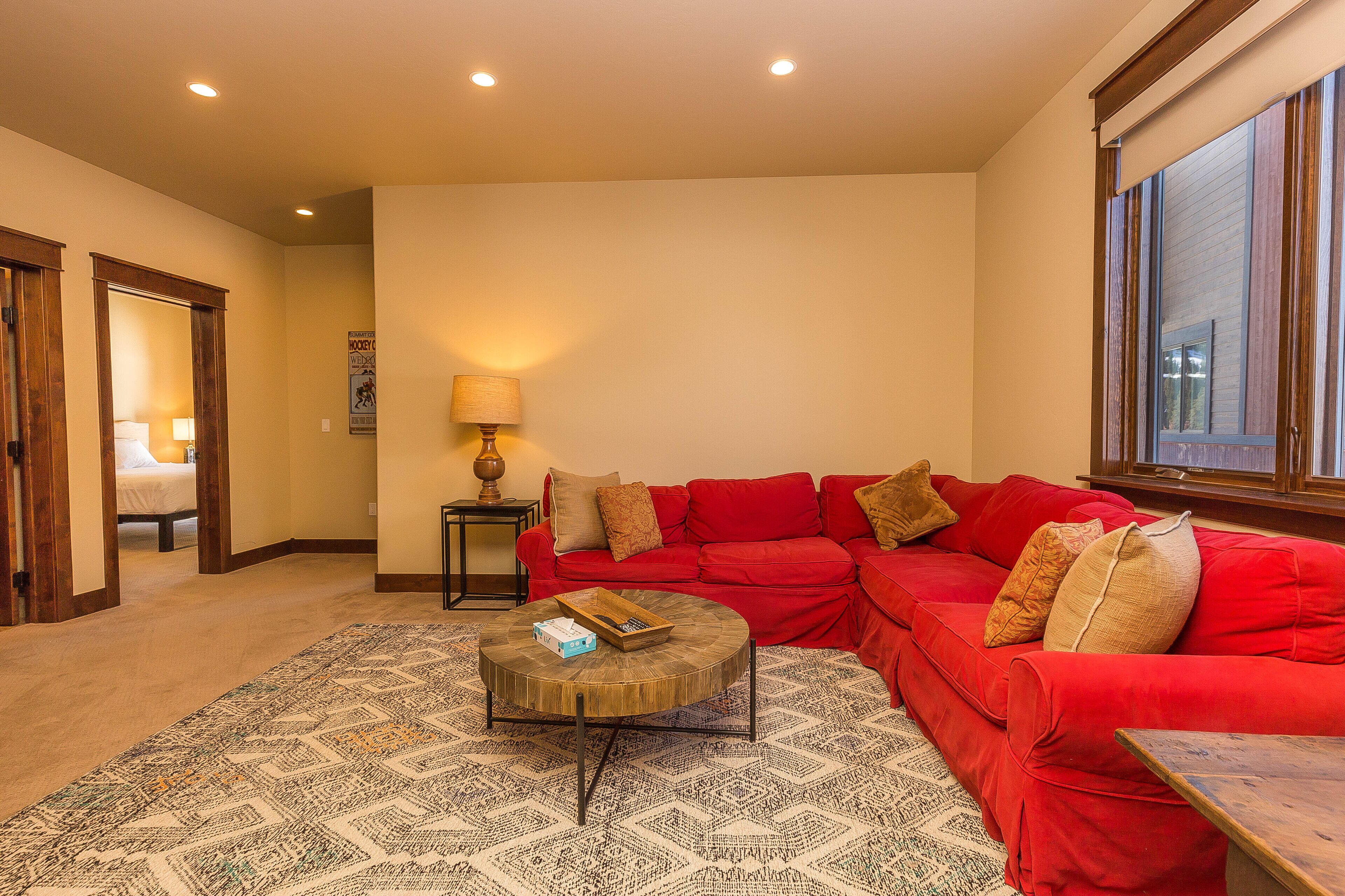 A living room with a red sectional sofa, a patterned rug, and a wooden coffee table.