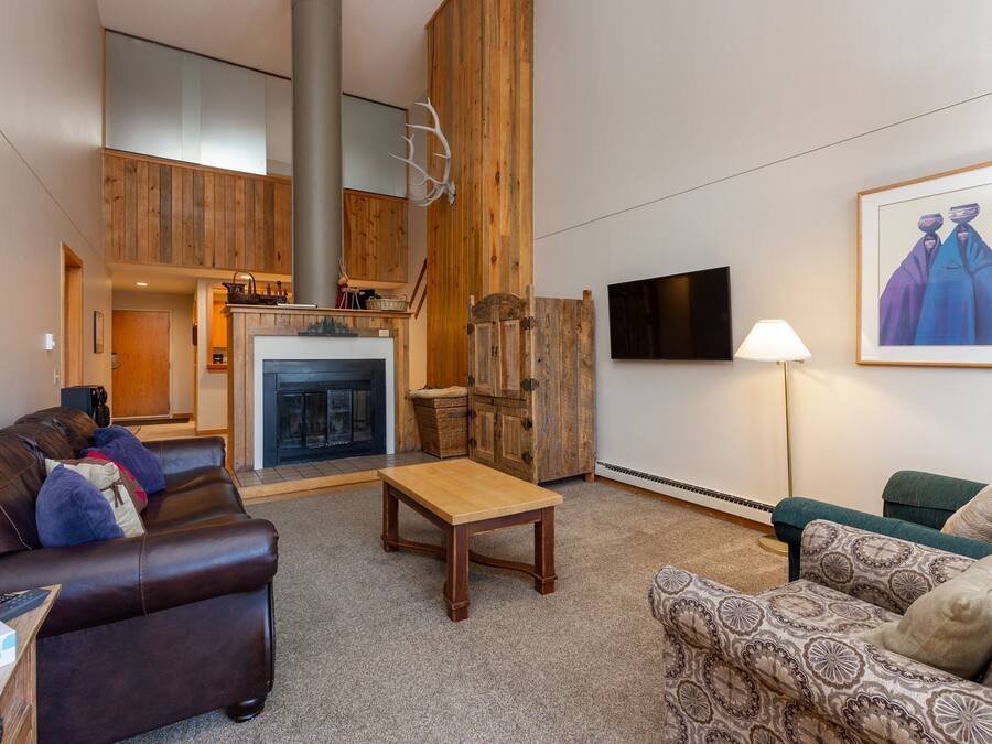 A spacious living room with a fireplace, wooden accents, a television, and a large painting.