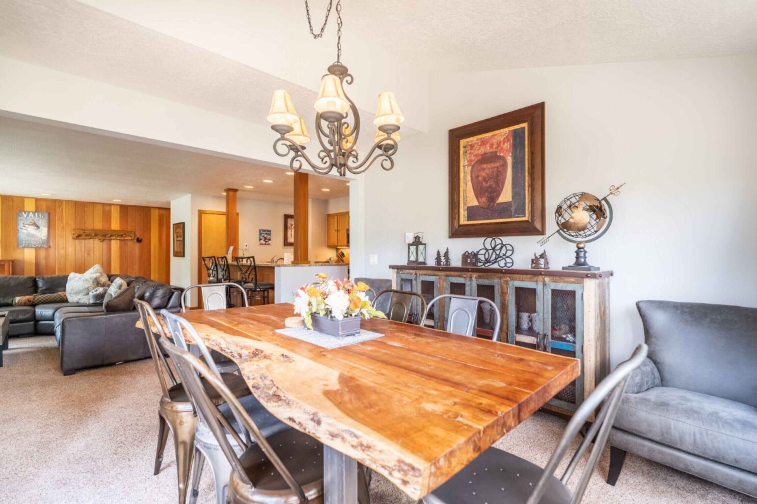 Un salón amplio con una mesa de comedor de madera, sofá de cuero y una araña.