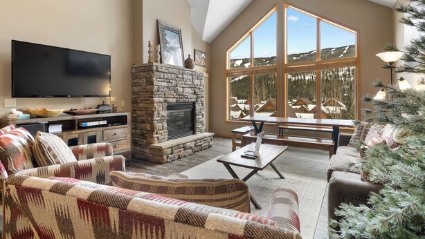A spacious living room with a stone fireplace, a flat-screen TV, and a large window offering a mountain view. - Gw5095-3 (Keystone)