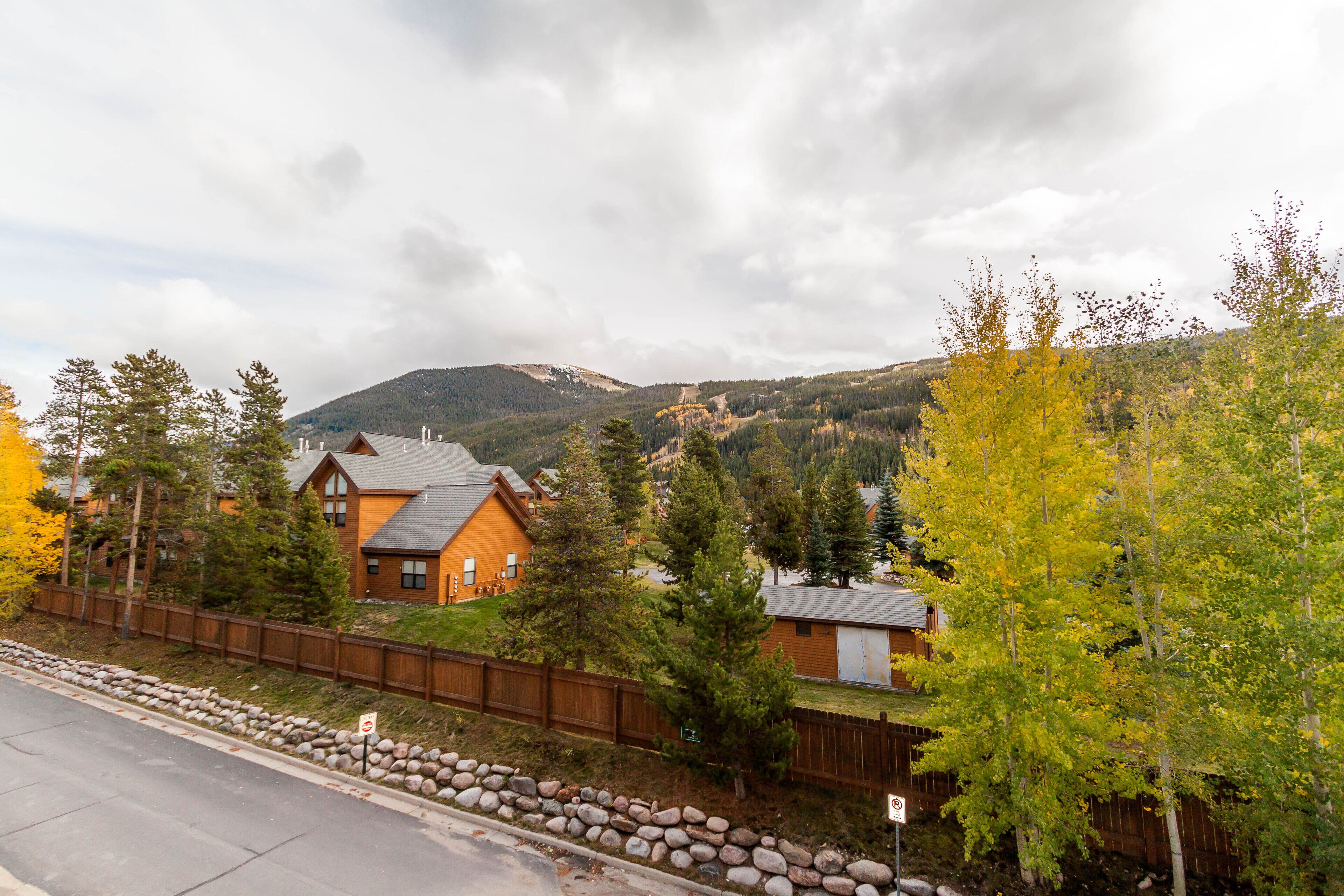 A residential area with houses, a wooden fence, and a mountain in the background.