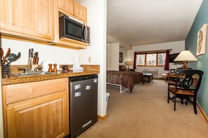 Cozy living space with a kitchenette, sofa, dining table, and carpeted floor.