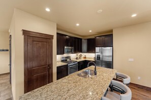 A modern kitchen with dark wood cabinets, stainless steel appliances, and a granite countertop.