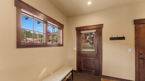 A hallway with a bench, a wooden door, and a window with a view of houses and trees. - Alders #801 by Summit County Mountain Retreats (Keystone)