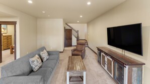 A living room with a grey sofa, a wooden coffee table, a brown armchair, and a TV on a wooden cabinet. - Alders #801 by Summit County Mountain Retreats (Keystone)