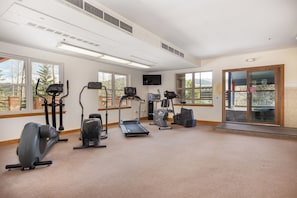 A gym with cardio machines, a TV, and large windows. - River Mountain Lodge #113w by Summit County Mountain Retreats (Breckenridge)