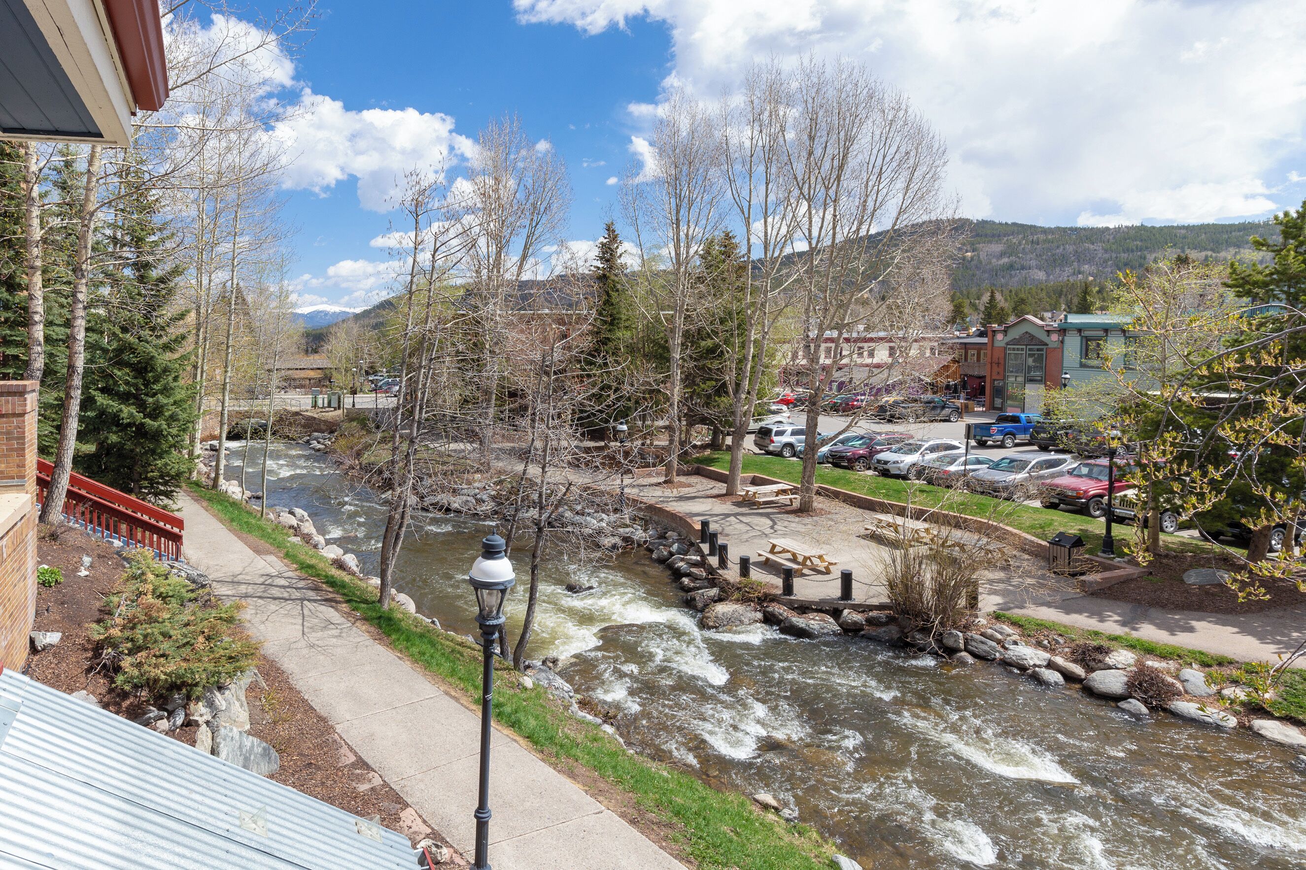 A view of a river with a bridge, a parking lot, and buildings in the background.