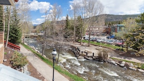 Vista de un río con un puente, un estacionamiento y edificios al fondo.