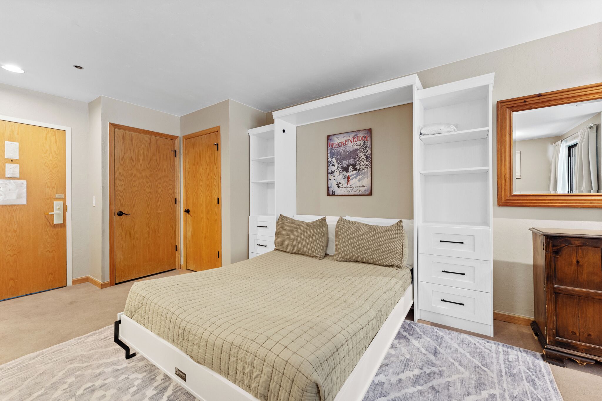 Un dormitorio con cama, estanterías empotradas, armario y espejo.