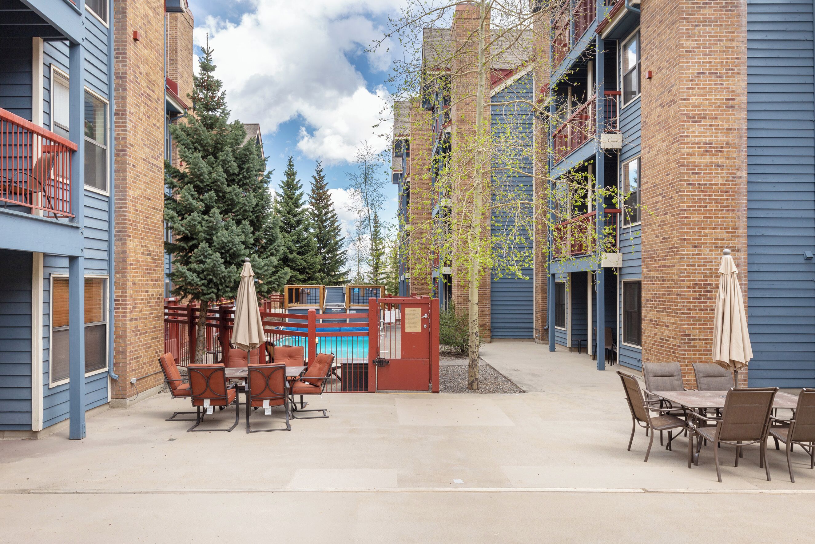 An outdoor patio area with a pool table, chairs, and umbrellas.
