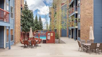 An outdoor patio area with a pool table, chairs, and umbrellas.