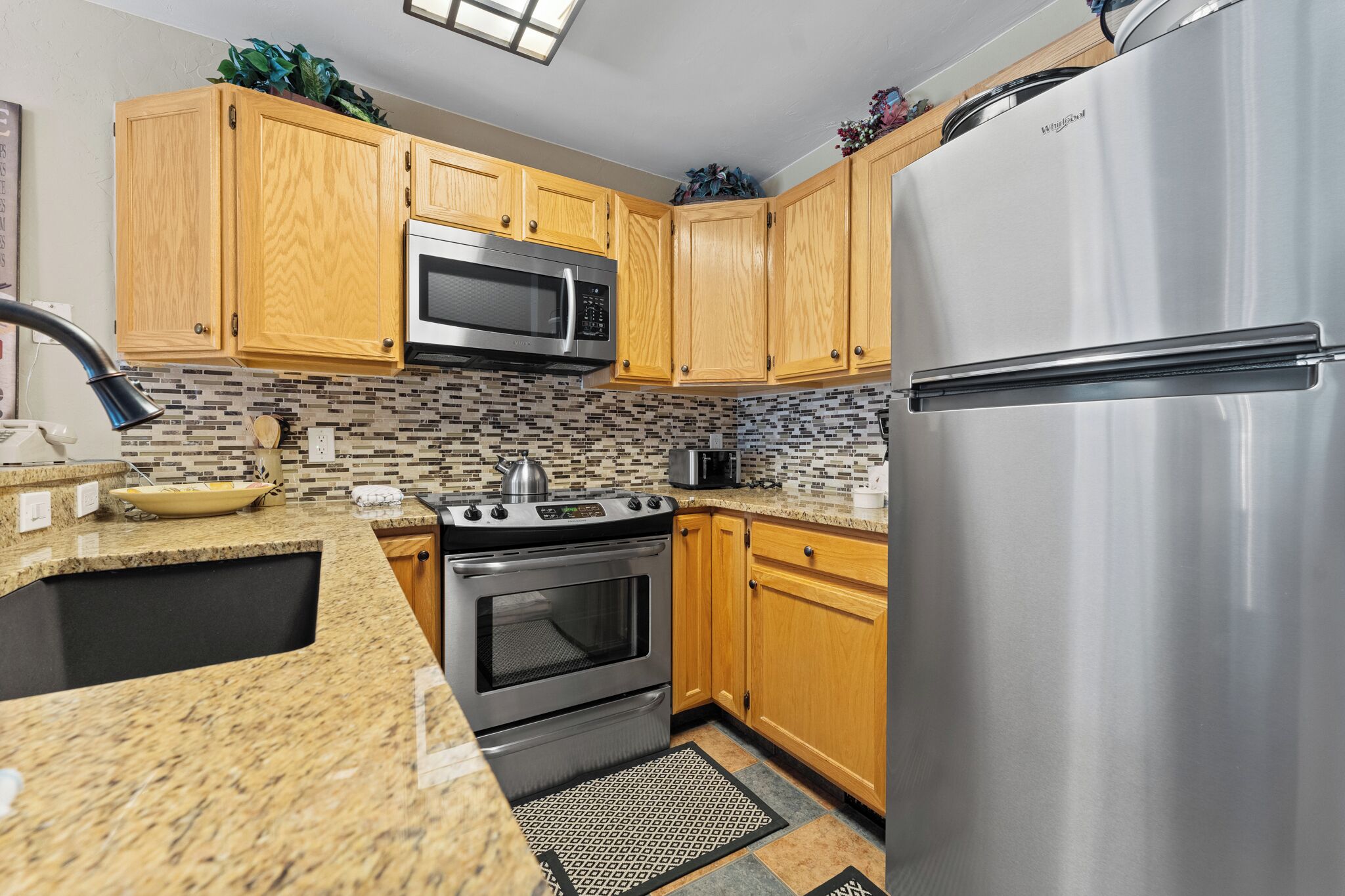 A kitchen with wooden cabinets, a stainless steel refrigerator, a microwave, and a stove.