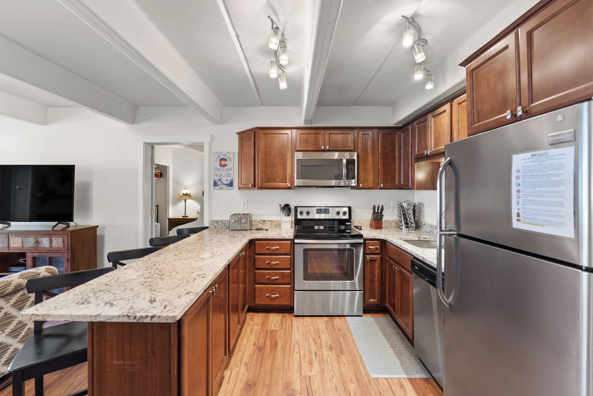 A modern kitchen with wooden cabinets, stainless steel appliances, and a granite countertop.