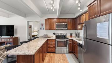 A modern kitchen with wooden cabinets, stainless steel appliances, and a granite countertop.