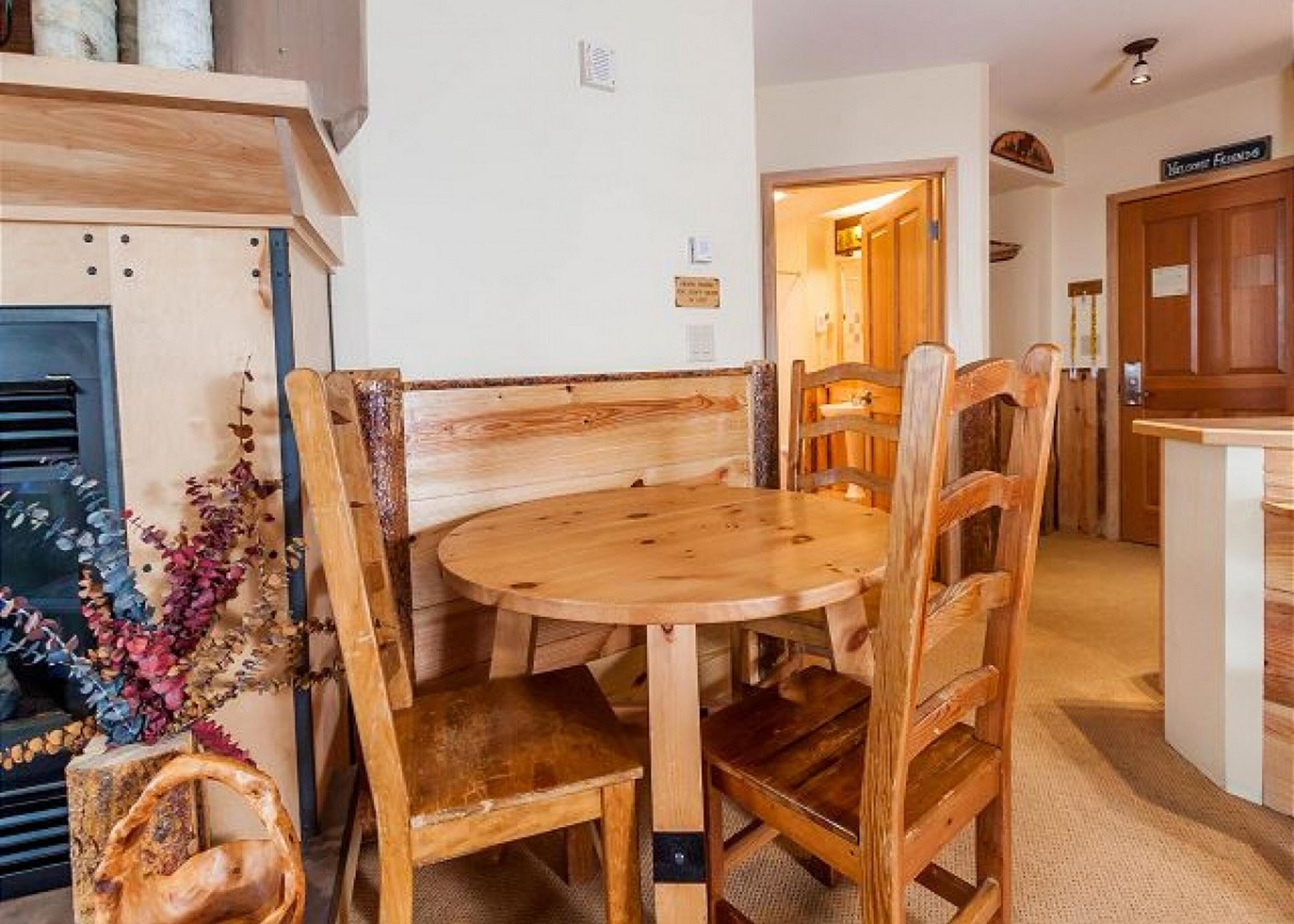 A wooden dining table with chairs, a bench, and a decorative plant.