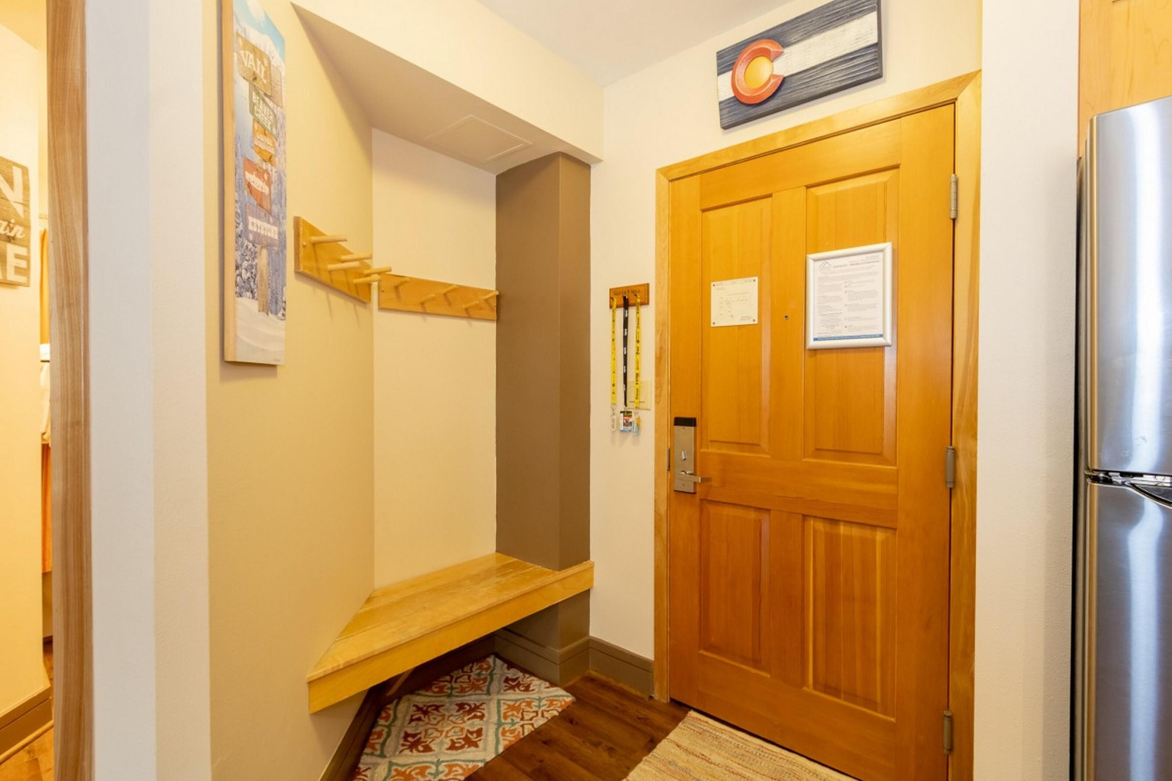Un couloir avec une porte en bois, un réfrigérateur et un tapis à motifs.