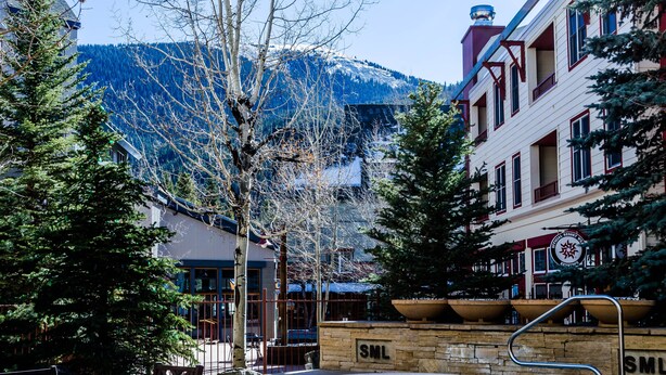 A courtyard with outdoor seating, a stone fountain, and buildings with a mountain backdrop. - Silver Mill by Summit County Mountain Retreats (Keystone)