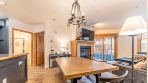 A modern kitchen with a wooden table, bench seating, a chandelier, and a fireplace. - Silver Mill by Summit County Mountain Retreats (Keystone)