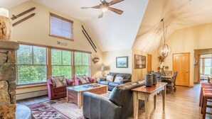 A spacious living room with a fireplace, large windows, and a dining area. - Jackpine Lodge by Summit County Mountain Retreats (Keystone)