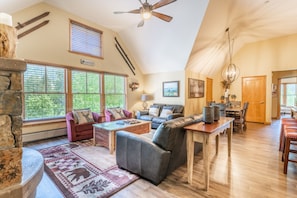 A spacious living room with a fireplace, large windows, and a dining area.