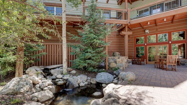 A stone water feature surrounded by rocks and a wooden deck with outdoor seating. - Jackpine Lodge by Summit County Mountain Retreats (Keystone)