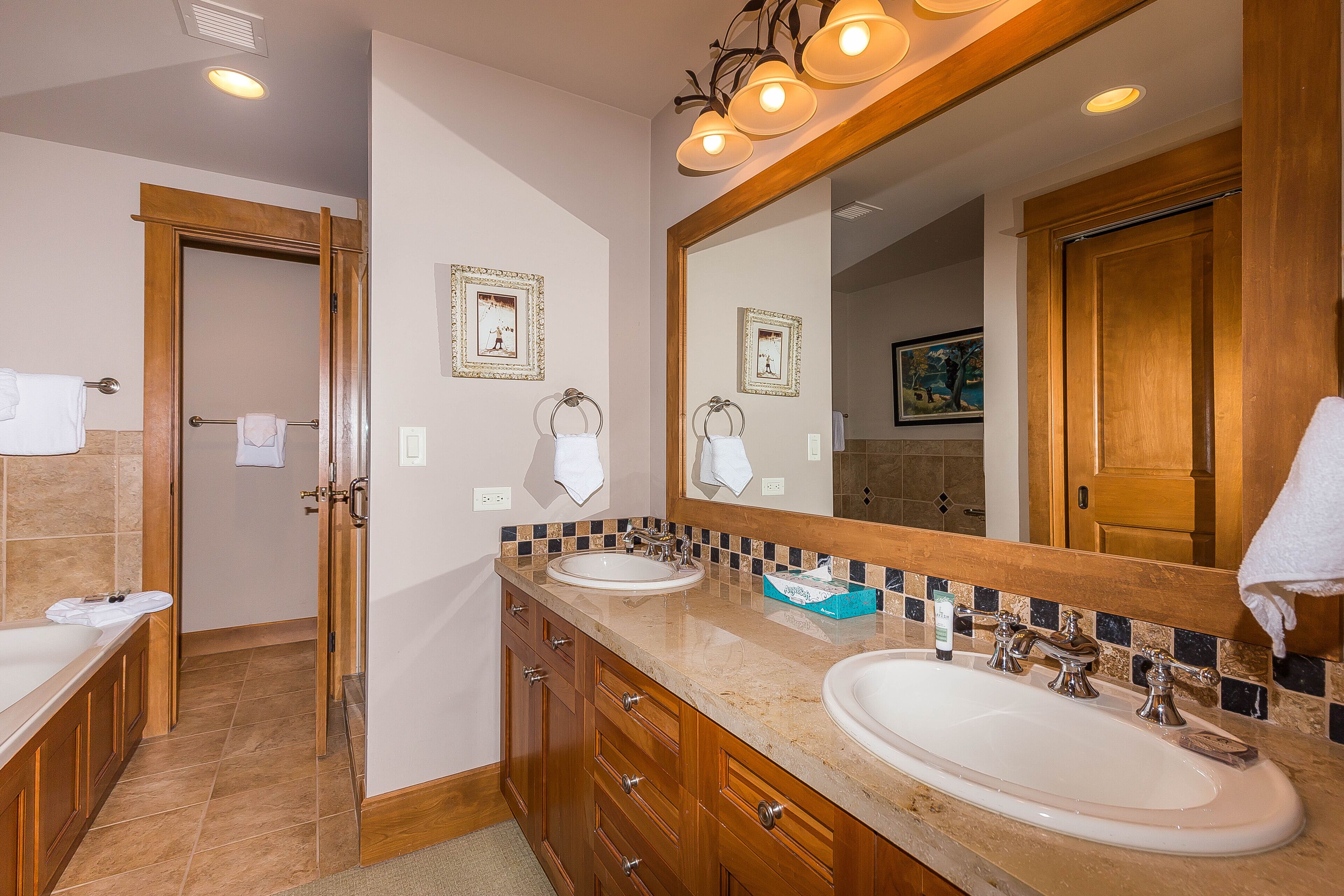 A bathroom with two sinks, a large mirror, and wooden cabinets.
