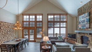 A spacious living room with a high ceiling, a fireplace, a television, and a dining area with a long table and chairs. - Lone Eagle by Summit County Mountain Retreats (Keystone)