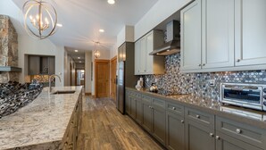 A modern kitchen with a marble countertop, stainless steel appliances, and a backsplash with a geometric pattern. - Lone Eagle by Summit County Mountain Retreats (Keystone)